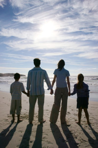 Young Couple with Two Children (8-12) Walking on the Beach --- Image by © Royalty-Free/Corbis